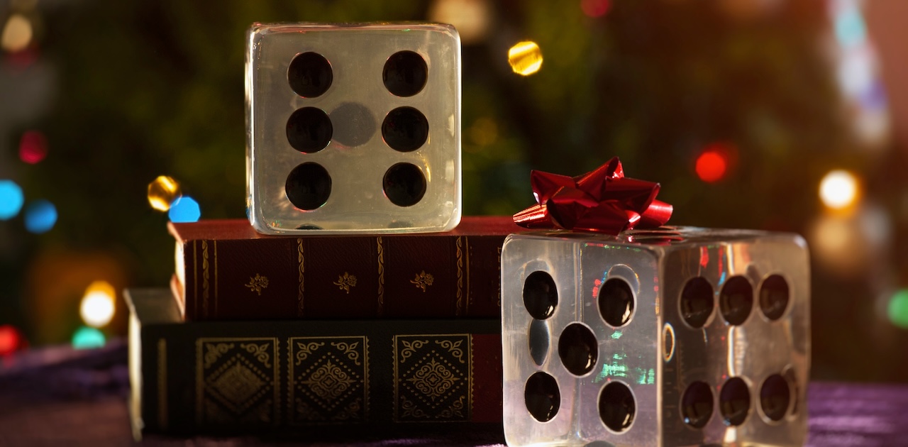 A pair of dice with a ribbon in front of a christmas tree.